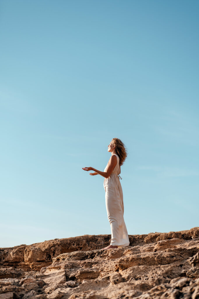 woman standing on cliff with a blue sky